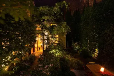 a house at night with a person walking into it at Carriage House in quiet ecological garden in Antwerp
