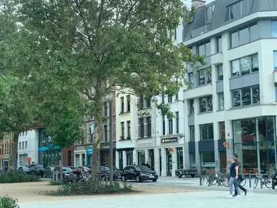 a couple of people walking down a city street at Royal South - Apartment Antwerp with Parkview in Antwerp