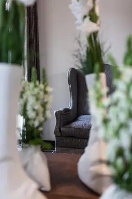 a living room with a chair and a table with flowers at B&B Louis1924 in Dilbeek