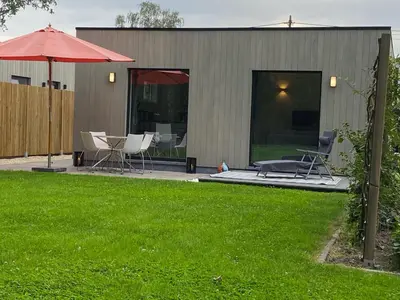 a patio with chairs and an umbrella in a yard at Bella Vie, rust en ontspanning in Haacht