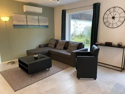 a living room with a couch and a table and a clock at Bella Vie, rust en ontspanning in Haacht