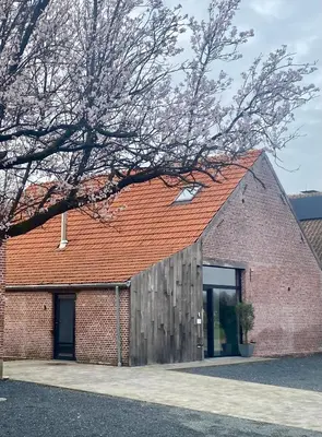 a brick building with a red roof at Hoeve De Kleinheide - De Schuur in Dessel