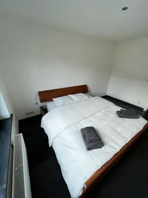 a bedroom with a large bed with white sheets and pillows at Casa Alness in Wetteren