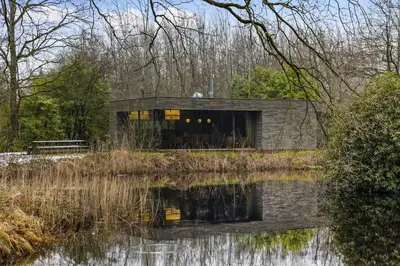 a house in the middle of a body of water at Stylish lakehouse in idyllic, private green scenery in Stekene