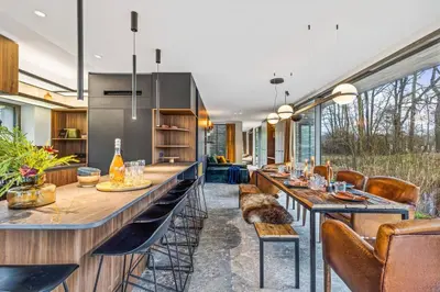 a kitchen with a long bar with a cat sitting on a bench at Stylish lakehouse in idyllic, private green scenery in Stekene