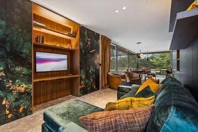 a living room with a couch and a television at Stylish lakehouse in idyllic, private green scenery in Stekene