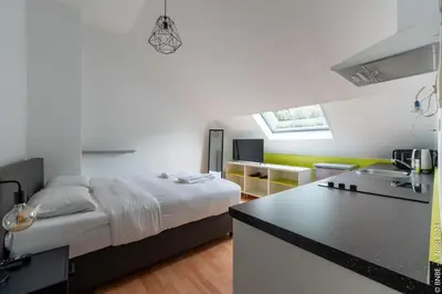a bedroom with a bed and a kitchen with a counter at La Louve - Big Place & Garden - Parking Gratuit in Brussels