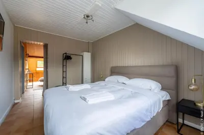 a large white bed with white sheets and pillows at La Louve - Big Place & Garden - Parking Gratuit in Brussels