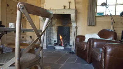 a living room with a fireplace and a rocking chair at B&B Hemel & Haard in Assenede