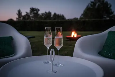 two wine glasses sitting on a table with a fire in the background at De verloren hoek in Aarschot