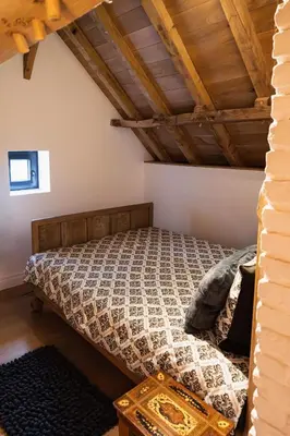 a bedroom with a bed in a room with wooden ceilings at Het Ovenhuisje in Denderwindeke