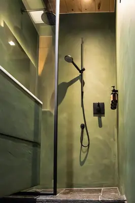 a shower stall with a shower head on a wall at Het Ovenhuisje in Denderwindeke