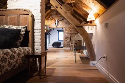a room with a bed and a wooden floor at Het Ovenhuisje in Denderwindeke