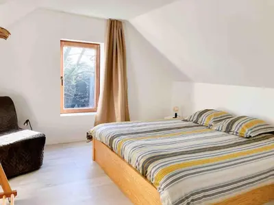 a bedroom with a bed and a chair and a window at Maison Raymond - Vakantiehuisje met houtgestookte sauna in Melsen