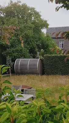 a large barrel sitting in the middle of a yard at Maison Raymond - Vakantiehuisje met houtgestookte sauna in Melsen