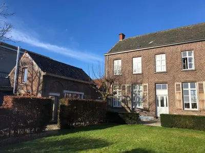 an old brick house with a fence in the yard at Maison Raymond - Vakantiehuisje met houtgestookte sauna in Melsen