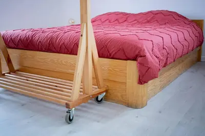 a wooden bed with a red comforter on a wooden cart at Maison Raymond - Vakantiehuisje met houtgestookte sauna in Melsen
