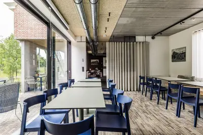 a dining room with tables and blue chairs at Gare 55 in Evergem