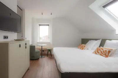 a bedroom with a large bed and a flat screen tv at Gare 55 in Evergem