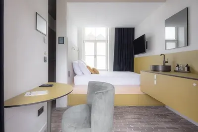 a room with a bed and a desk and a table at Gare 55 in Evergem