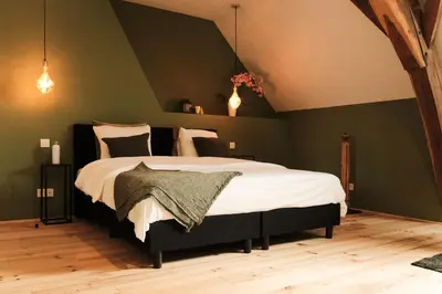 a bedroom with a large bed with green walls at De Pastorie Alsemberg B&B in Beersel