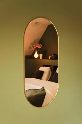 a mirror hanging on a green wall with a bed at De Pastorie Alsemberg B&B in Beersel