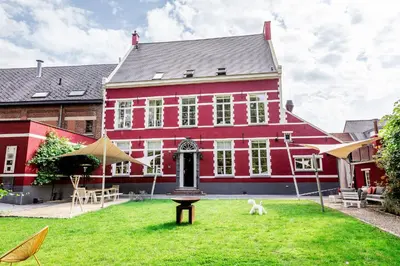 a large red house with a dog in the yard at De Pastorie Alsemberg B&B in Beersel
