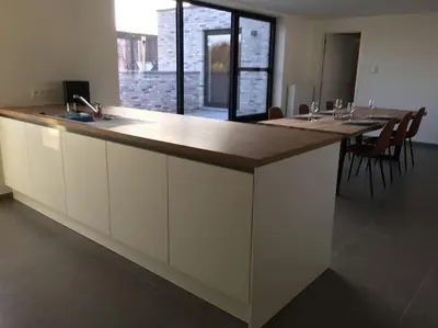 a large kitchen with a large counter with tables and chairs at Leuk overnachten in hartje Laarne, dicht bij Gent! in Laarne