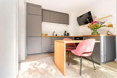 a kitchen with a wooden table and pink chairs at Luxe-Avontuur in een Romantische Cabin in het Bos in Stekene