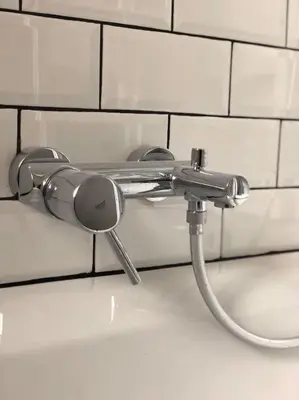 a water hose hooked up to a white tiled wall at Quartier Diamant in Brussels