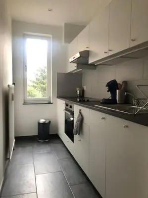 a kitchen with white cabinets and a window at Quartier Diamant in Brussels