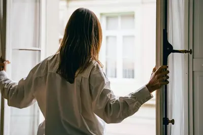 a woman opening the door to a window at Hotel des Galeries in Brussels