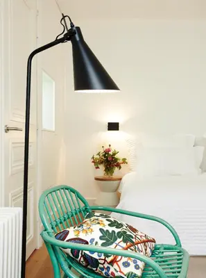 a black lamp and a green chair in a bedroom at Hotel des Galeries in Brussels