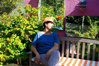a woman wearing a hat sitting on a bench at Guest House Les 3 Tilleuls in Brussels