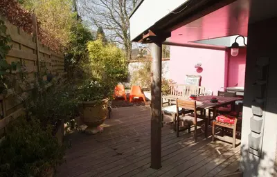 a patio with a table and a pink house at Guest House Les 3 Tilleuls in Brussels