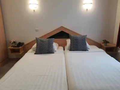 two beds in a hotel room with white sheets at Hotel New Flanders in Sint-Niklaas