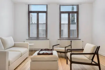 a living room with a couch and chairs and windows at The 1894 Residence by Domani Hotels in Antwerp
