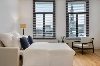 a bedroom with a bed and a couch and windows at The 1894 Residence by Domani Hotels in Antwerp