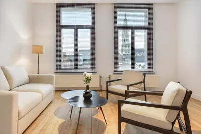 a living room with a couch and chairs and windows at The 1894 Residence by Domani Hotels in Antwerp