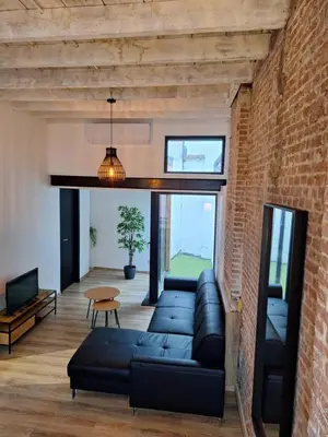 a living room with a couch and a brick wall at Huis ALNA 4 in Mechelen