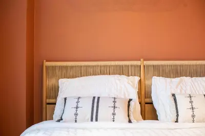 a bed with two pillows on it with an orange wall at Romantische Studio in Harmoniewijk in Antwerp