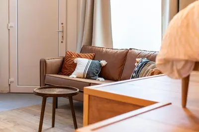 a living room with a brown couch and a stool at Romantische Studio in Harmoniewijk in Antwerp