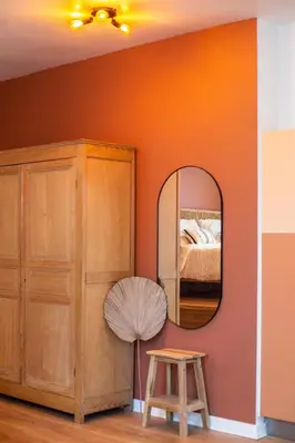 a bedroom with an orange wall with a mirror at Romantische Studio in Harmoniewijk in Antwerp