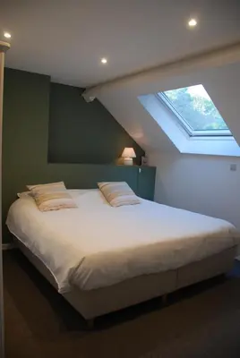 a bedroom with a large bed with a window at The Little House in Beersel