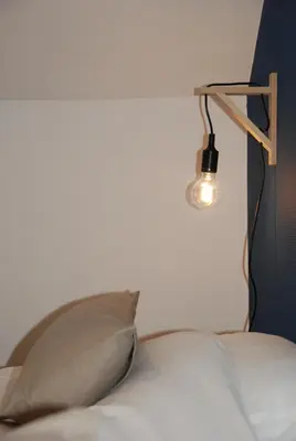 a bed with a pillow and a light on the wall at The Little House in Beersel