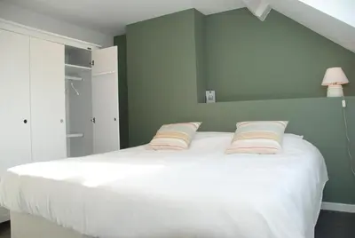 a bedroom with a large white bed with two pillows at The Little House in Beersel