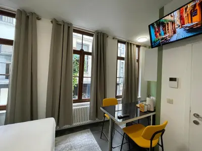 a room with a desk and chairs and windows at Apartament in Brussels