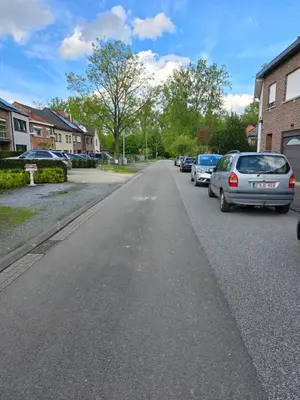 an empty street with parked cars in a residential neighbourhood at Le gîte des Ambres in Denderleeuw