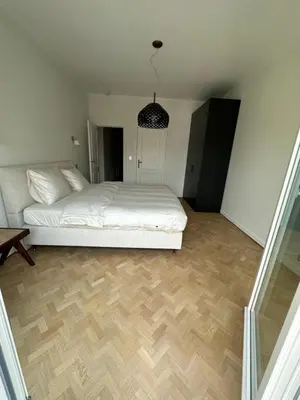 a bedroom with a white bed and a wooden floor at Cosy apartment with park view in Ghent