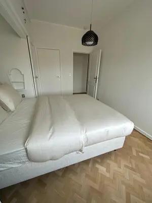 a large white bed in a room with a wooden floor at Cosy apartment with park view in Ghent